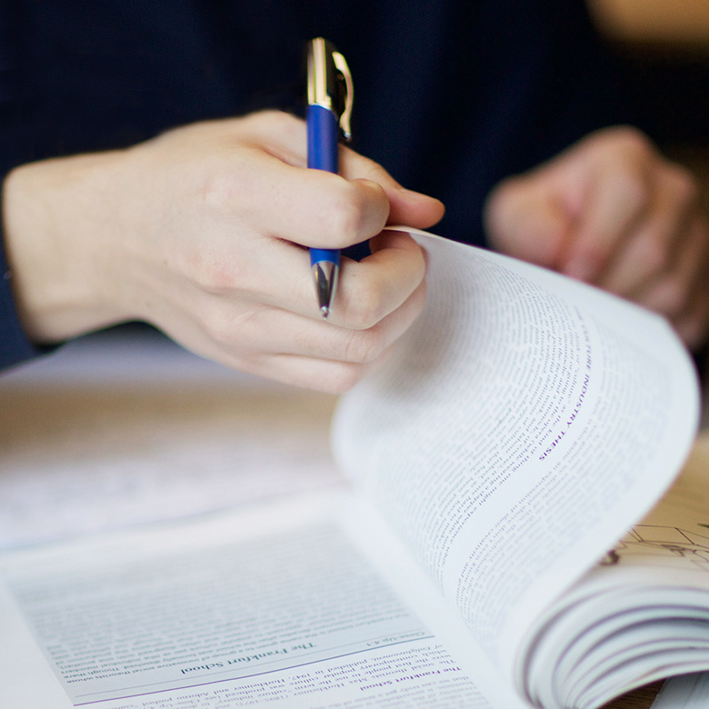 Person holding a pen and reading a book.